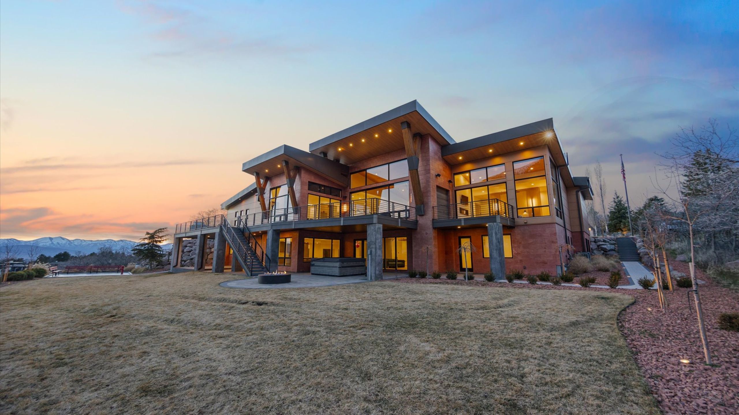 Rear view of property featuring a patio, a balcony, a lawn, and a fire pit